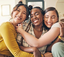 Group of friends smiling while hugging on couch