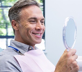 Man in dental chair looking at his smile