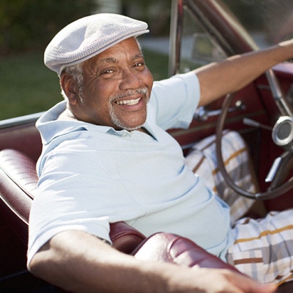 An older gentleman driving a classic convertible and smiling after receiving All-On-4 in Fargo