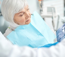 An older woman looks at a dental X-ray of her smile while listening to her dentist