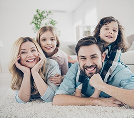 Family smiling together laying on the ground inside