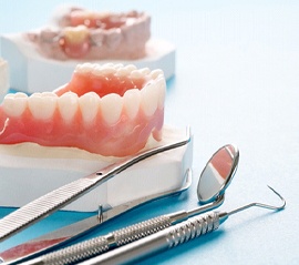 Full denture next to dental instruments and dental model