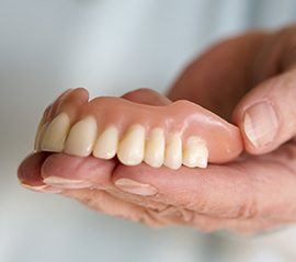 Hand holding a full denture