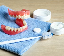 Dentures on a towel with a brush nearby