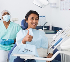 A smiling woman at the dentist’s office giving a thumbs up