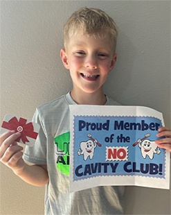 Young boy holding a sign that says proud member of the no cavity club