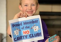 Young girl holding a sign that says proud member of the no cavity club
