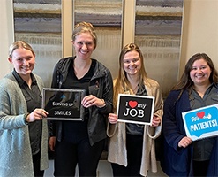 Dental team members holding signs in Fargo dental office