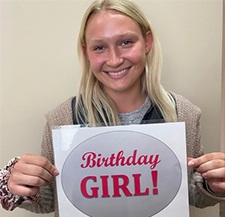 Young woman holding a birthday girl sign in Fargo dental office
