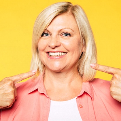 Happy senior woman pointing at her implant dentures in Fargo