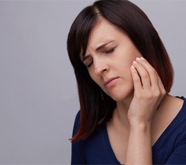 a woman holding her jaw due to failed dental implant
