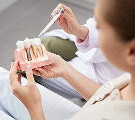 dentist showing a patient a model of how dental implants work