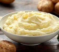 Bowl of mashed potatoes surrounded by potatoes