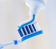 Squeezing toothpaste onto a blue toothbrush