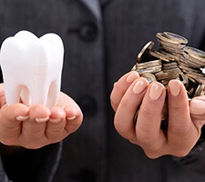 Person holding tooth and money for dental implants in Fargo