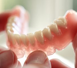 Person holding a denture for dental implants in Fargo