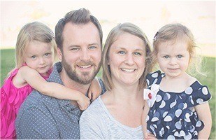 Mother father and two kids smiling outdoors