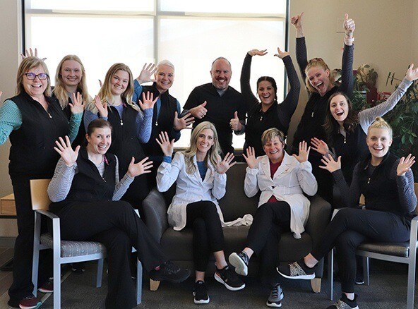 Dentists and dental team members smiling and holding their hands up in Fargo dental office