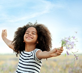 child playing in a field, picking flowers