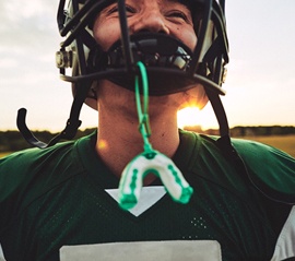 Football player with mouthguard hanging from facemask