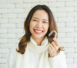 Smiling woman holding aligner tray