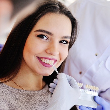 Woman's smile compared with tooth color chart