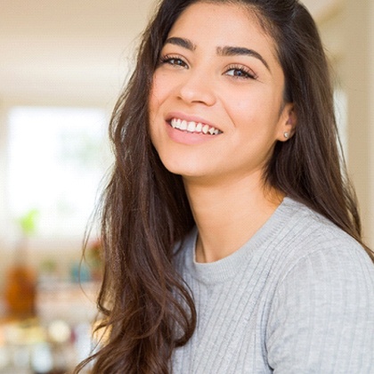 Closeup of woman in grey shirt smiling with white teeth