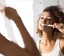 Woman in white shirt brushing her teeth