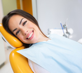 A smiling woman laying in a dentist’s chair