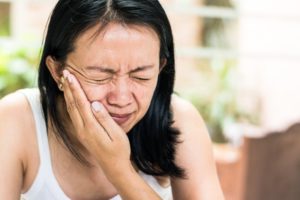 woman holding mouth in pain who needs emergency dentist in Fargo 