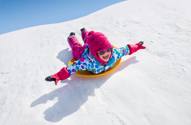 Picture of a smiling child sledding in the snow