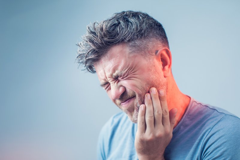 patient with TMJ disorder holding cheek